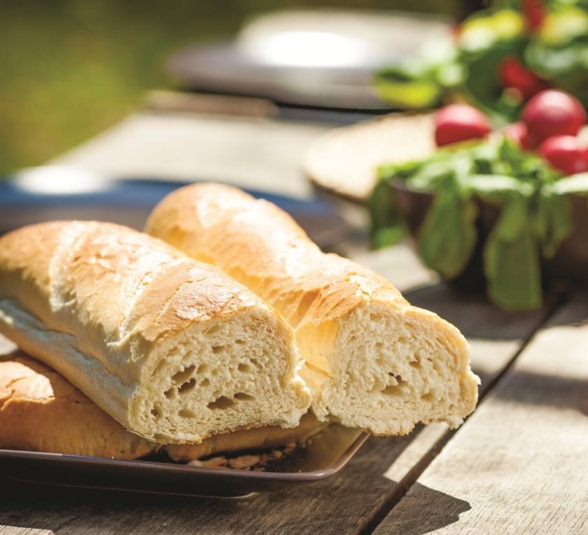 Fresh bread on a rustic table in front of salad