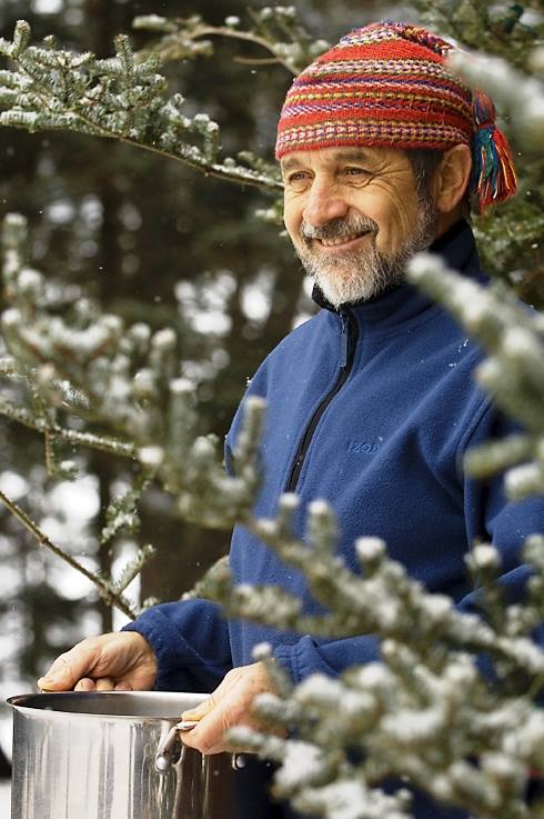 Man in beanie holding large pot outside in the snowy trees
