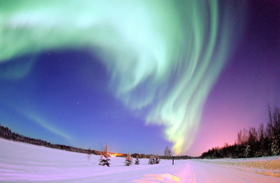 Northern lights at dusk over a snowy clearing
