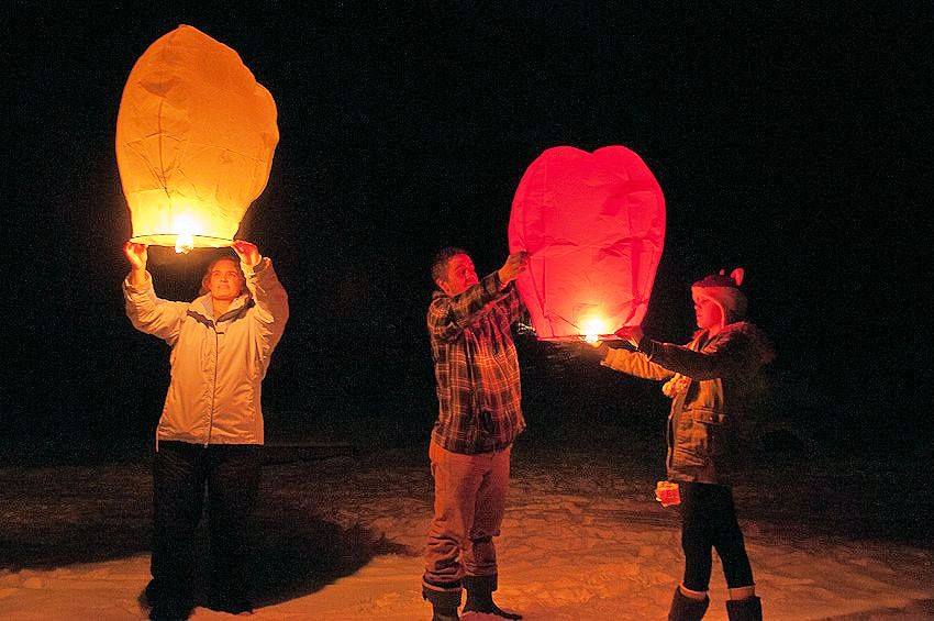 Three people lighting hot air lamps to throw into the sky